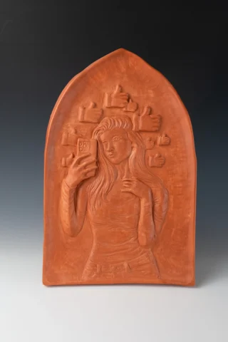 Bas relief carving of a modern woman taking a selfie
