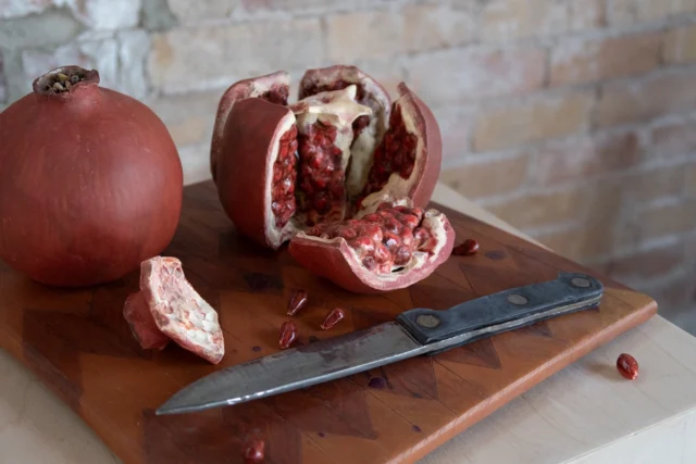 Ceramic pomegranates, knife, and cutting board