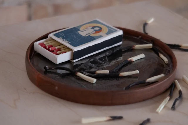Ceramic matchbox, matches (some burnt) on a mirrored dish